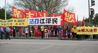 Falun Gong practitioners hold banners in front of Xi's hotel. The white banners with blue and black texts read: “Bring Jiang Zemin to Justice.”