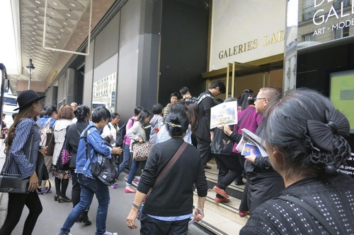 e52d74141bae8a997221f4e8a9c16ef2 Chinese tourists read Falun Gong informational materials in front of Galeries Lafayette.