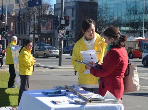 Passersby pause to watch the event and sign a petition supporting the prosecution of former Chinese leader Jiang Zemin.