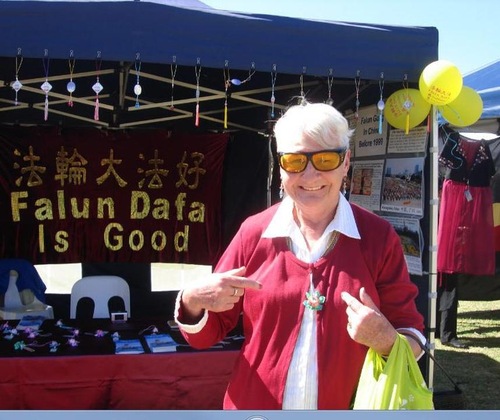 A festivalgoer wears the paper lotus flower she received at the Falun Gong booth.