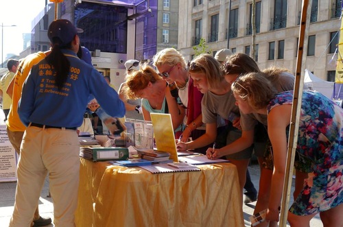 Passersby sign petitions and take photos.