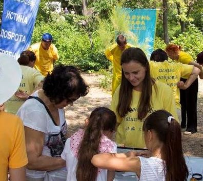 capture-1 Lyudmila (long hair in yellow T-shirt) at a Falun Gong event.