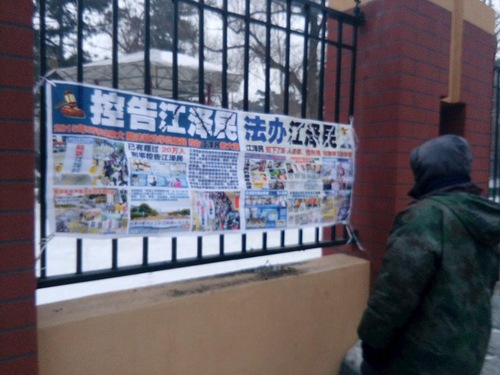 69858b91866eff2ce0d99a0ac63e2a59 A passerby in Changchun City, Jilin Province, reads a poster about bringing former Chinese leader Jiang Zemin to justice for persecuting Falun Dafa.