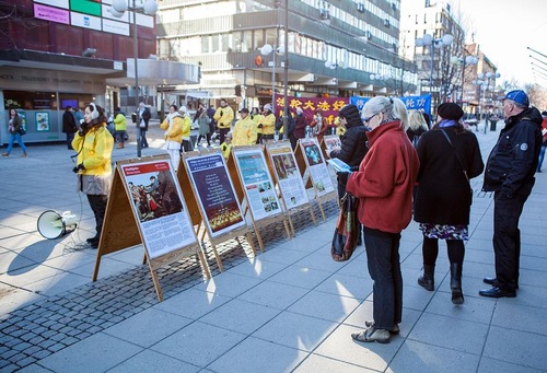 Passersby look at posters with Falun Gong information.