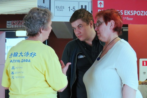 89d488ffa002f42d7281f2b39d266434 A Falun Dafa practitioner explaining the practice to a few visitors at the Expo.
