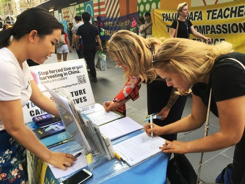 d1305e6c48cc2a8835bfba8a20ce97c8 On New Year's Eve in the busy area near the central train station in Melbourne, a Falun Gong practitioner invites passersby to sign a petition to help end the persecution in China.