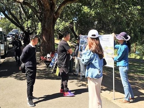 2c6bc745d1e35b054fa262d9a885920f Chinese tourists read information about Falun Gong and the persecution.