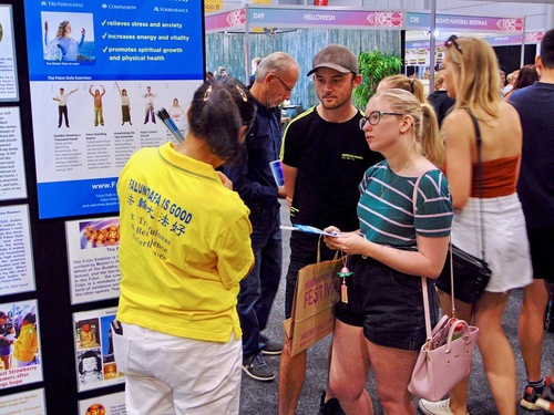 Visitors at the Falun Dafa stand learning about the practice.