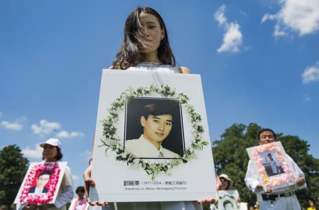 Falun Gong demonstrators hold memorial pictures as they march on Capitol Hill in Washington, DC
