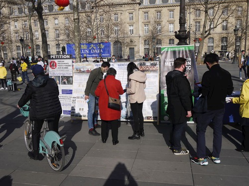 People stop by the practitioners' display on Place de la République and learn about Falun Dafa and the ongoing persecution in China.