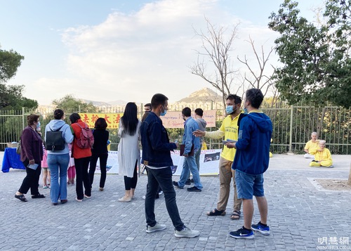 Locals observe Falun Dafa practitioners' awareness activities.