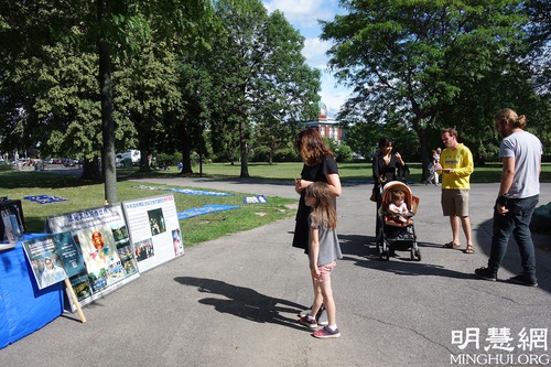 152d41cd42925e268455f39e3845e550 Passersby stop to read about Falun Dafa and the persecution in China.