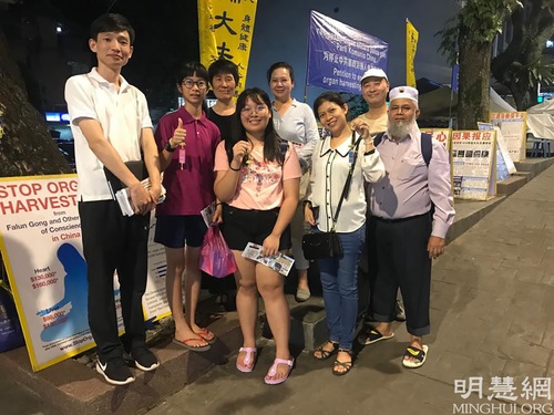 Tourists take photos with Falun Dafa practitioners to show their support.