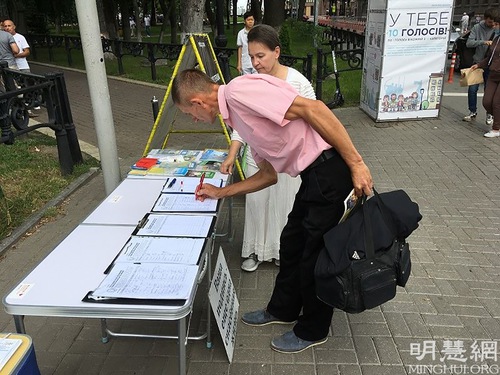Passersby sign the petition to call for an end to the persecution.