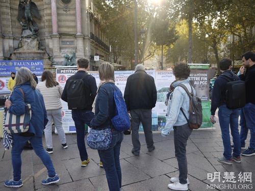 People stop to read about Falun Dafa and the persecution of the practice by the CCP.