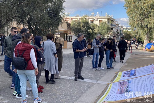On December 5, 2021, Falun Dafa practitioners clarify the truth on the street beside the Acropolis hill in Athens. Many people stopped to watched the Falun Gong information display boards.