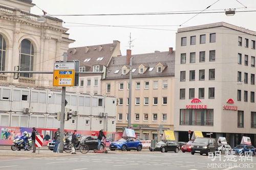 Falun Dafa practitioners’ car parade passes by the Staats Theater at the John-F.-Kennedy-Platz.