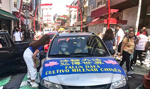 Car drives through the streets of Liberdade, playing Falun Dafa music.