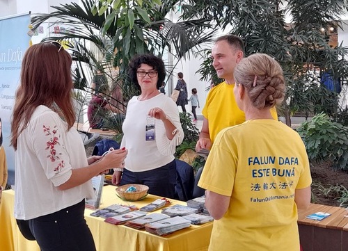 Visitors talk to practitioners at the Falun Dafa booth.