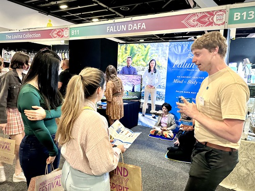 Visitors stop by the Falun Dafa booth and talk with practitioners.