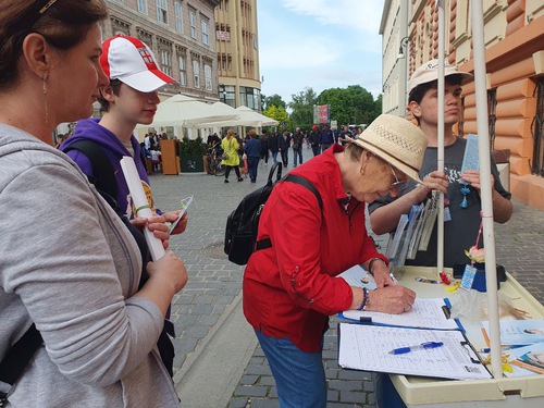 Members of a family in Ploiești sign the petition to stop the persecution in China.
