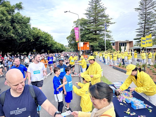 Crowds of runners on the road and Falun Gong practitioners on the roadside during the City2Surf Fun Run in Sydney on August 13, 2023
