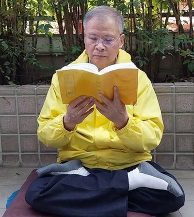 Zhuang Maoqin reads Zhuan Falun, the main book of Falun Dafa.