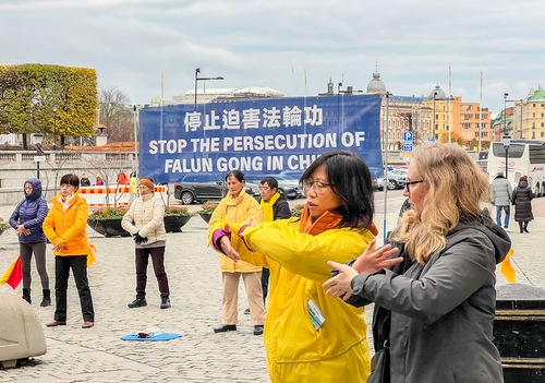 A lady learns to practice the Falun Dafa exercises.