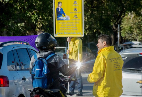 Practitioners hold signs and banners and explain the ongoing persecution in China and the principles of Falun Dafa to drivers when they stop for the traffic light.