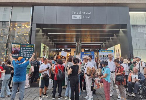 Chinese tourists learn about the persecution by reading display boards set up in front of the Shilla Duty Free Shop.